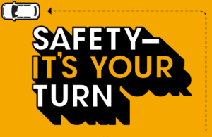 An image from the left turn safety education program that reads: "SAFETY - IT'S YOUR TURN" in black, white, and orange graphics with a car making a left turn at 90 degrees.